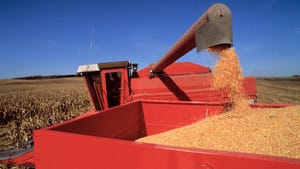 combine loading corn into grain cart against blue sky